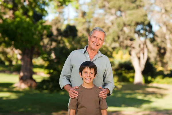 Grandfather with his grandson looking at the camera in the park — Stock Photo, Image