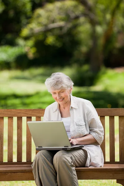 成熟的女人，她坐在板凳上的笔记本电脑工作的 — 图库照片