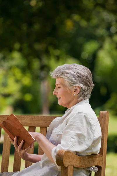 Reired 女人读一本书坐在板凳上 — 图库照片