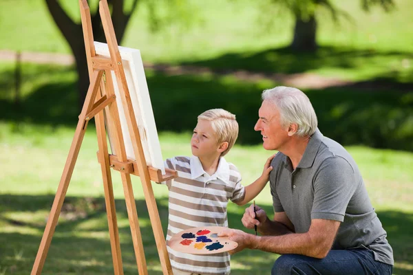 Abuelo y su nieto pintando en el jardín — Foto de Stock