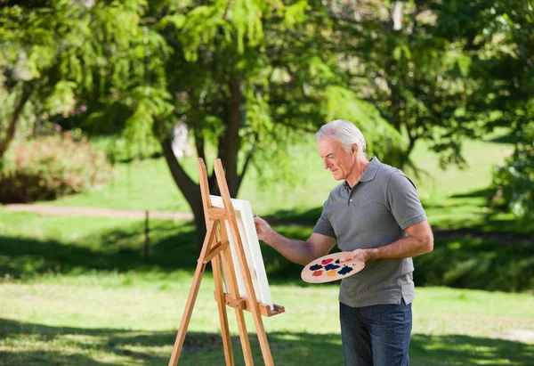 Старший чоловік малює в саду — стокове фото