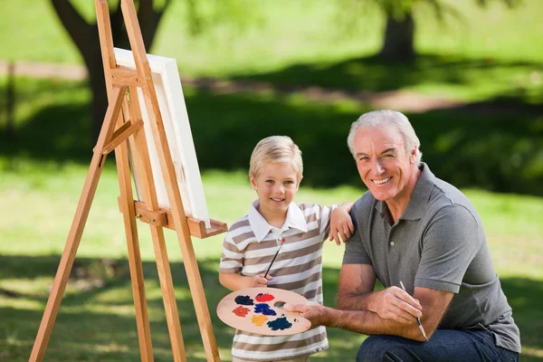 Дедушка и его внук рисуют в саду — стоковое фото
