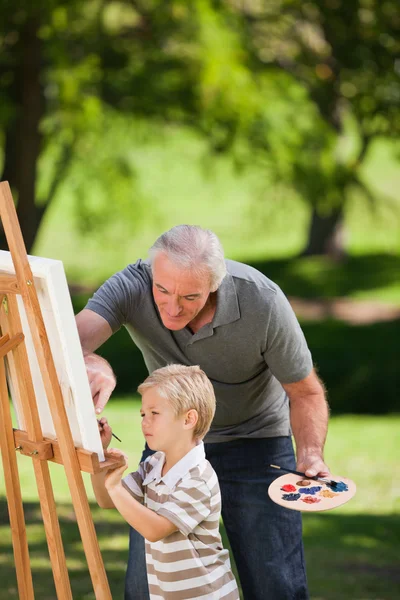 Grandfather and his grandson painting in the garden — Stock Photo, Image