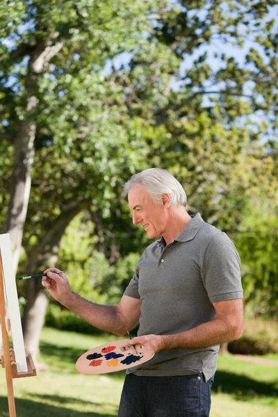 Mature man painting in the garden — Stock Photo, Image