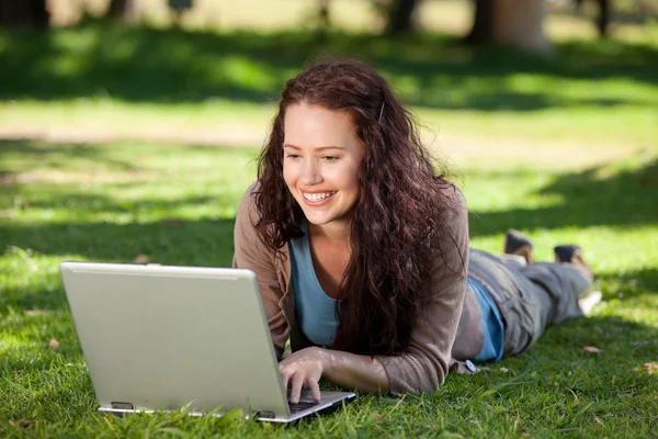 Женщина, работающая над ноутбуком в парке — стоковое фото