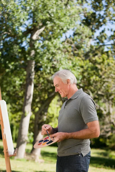 Mature man painting in the garden — Stock Photo, Image