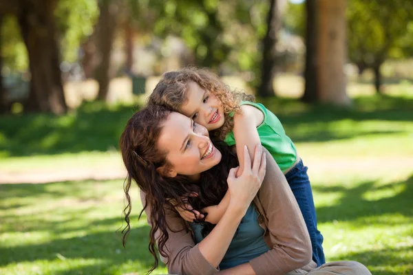 Woman hugging her daughter in the park — Stok fotoğraf