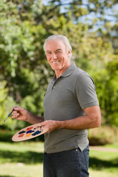 Зрелый человек рисует в саду — стоковое фото