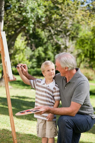 Happy Grandfather and his grandson painting in the garden — Stock Photo, Image