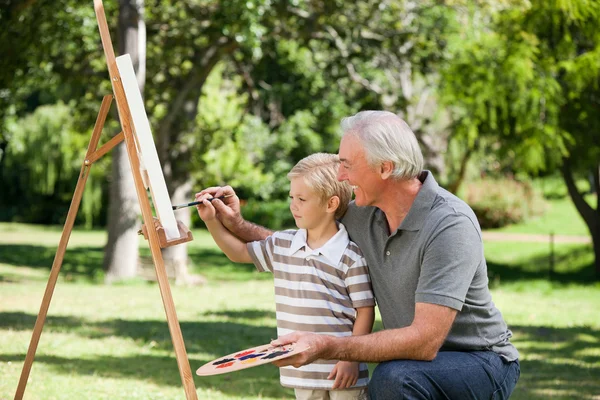 Happy Grandfather and his grandson painting in the garden — Stock Photo, Image