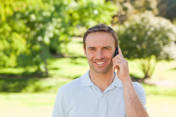 ハンサムな男が公園で電話をかける — ストック写真