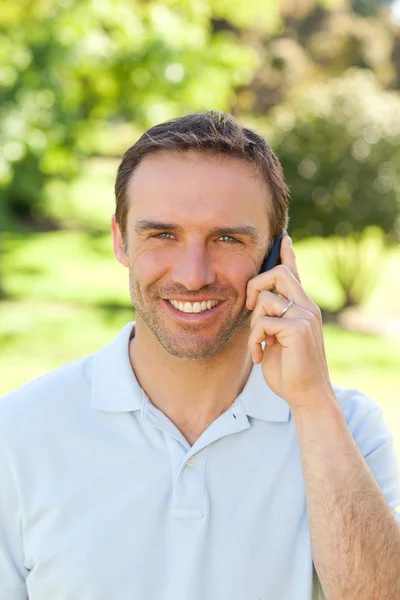 Handsome man phoning in the park — Stock Photo, Image