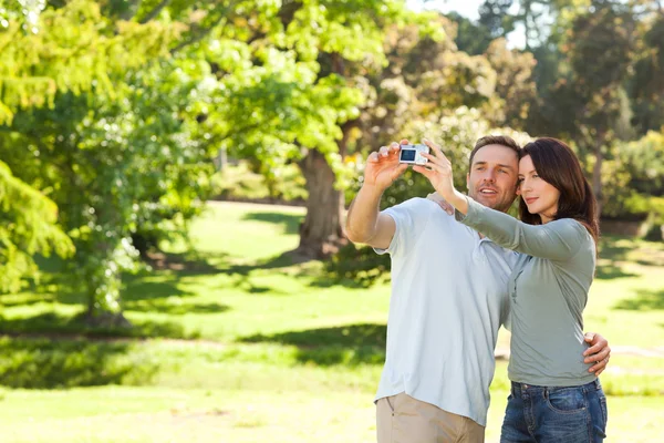 Casal tirando uma foto de si mesmos no parque — Fotografia de Stock
