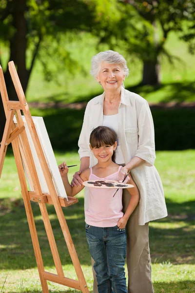 Grootmoeder en haar kleindochter schilderij in de tuin — Stockfoto