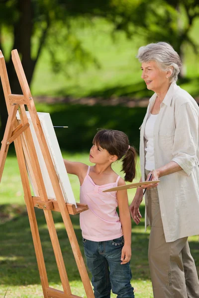 Babička a její vnučka, malování v zahradě — Stock fotografie