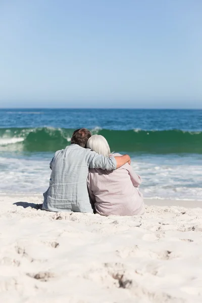 Para seniorów siedząca na plaży — Zdjęcie stockowe