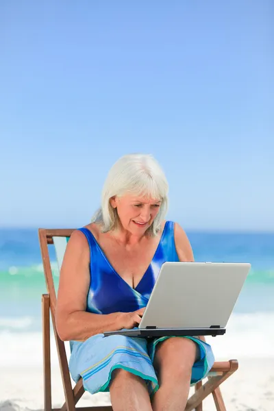 Vrouw die werkt op haar laptop op het strand — Stockfoto