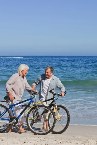 Retired couple with their bikes on the beach — Stock Photo, Image