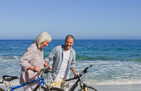 退休的夫妇与他们的自行车在海滩上 — 图库照片