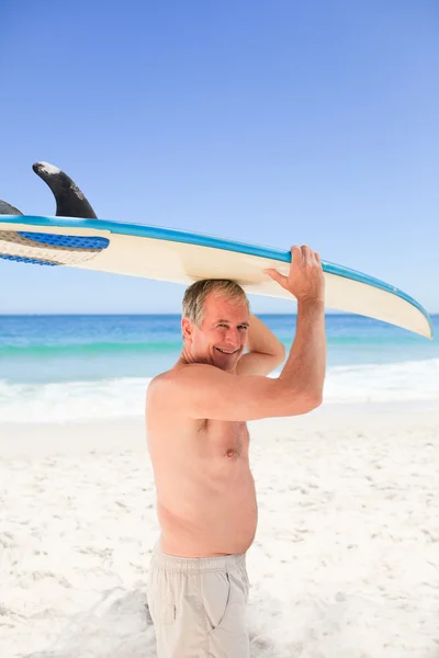 Gepensioneerde man met zijn surfplank — Stockfoto