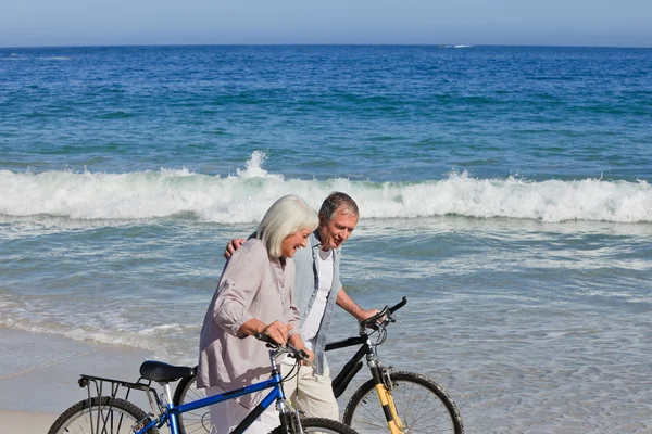 Retired couple with their bikes on the beach — Stock Photo, Image