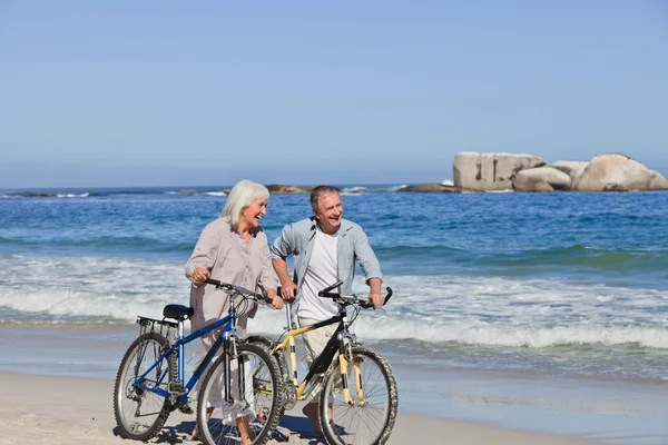 退休的夫妇与他们的自行车在海滩上 — 图库照片