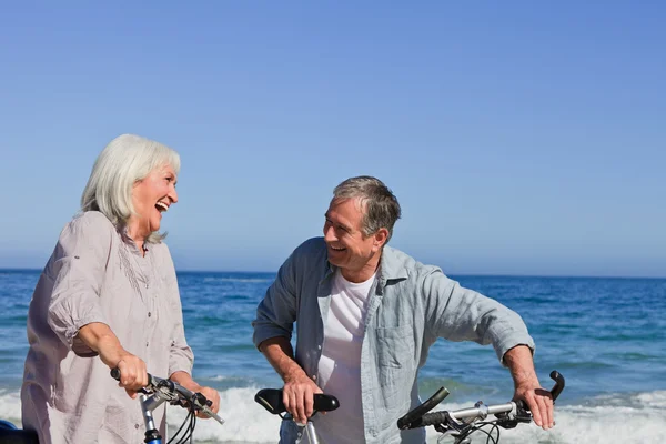 Casal aposentado com suas bicicletas na praia — Fotografia de Stock