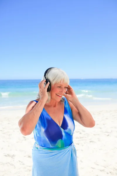 Kadın kıdemli deniz yanında biraz müzik dinlemek — Stok fotoğraf