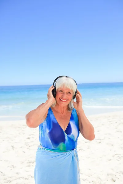 Ανώτερος γυναίκα ακούγοντας κάποια μουσική δίπλα στη θάλασσα — Φωτογραφία Αρχείου