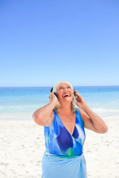 Mujer mayor escuchando algo de música al lado del mar —  Fotos de Stock