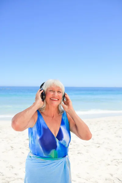 Старшая женщина слушает музыку у моря — стоковое фото