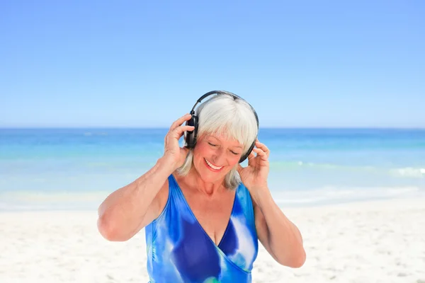 Старша жінка слухає музику біля моря — стокове фото