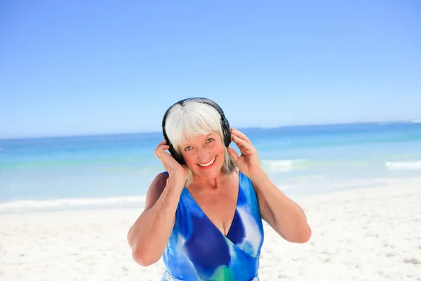Mujer mayor escuchando algo de música al lado del mar — Foto de Stock