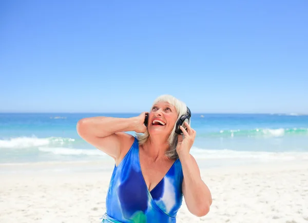 Starszy kobieta słuchać muzyki nad morzem — Zdjęcie stockowe