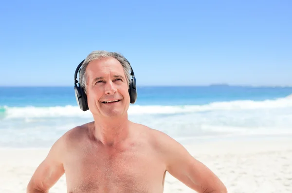Homem aposentado ouvindo música na praia — Fotografia de Stock