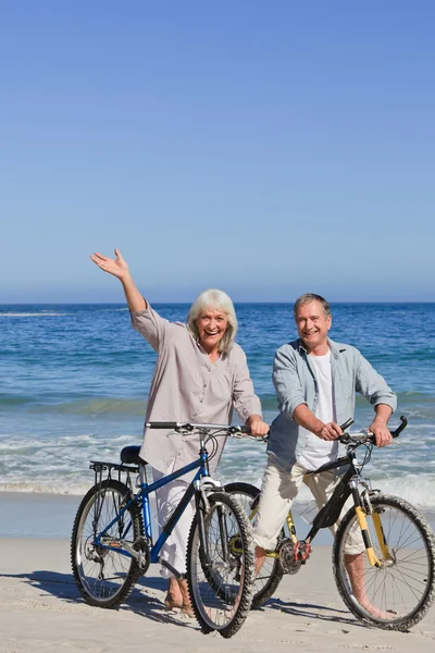 Casal maduro com suas bicicletas na praia — Fotografia de Stock