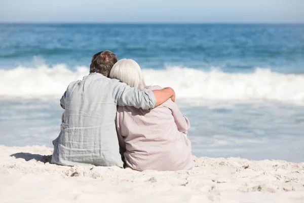 Пожилая пара, сидящая на пляже — стоковое фото