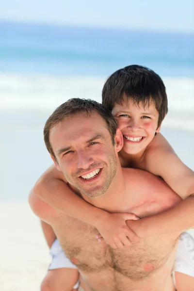 Far med son en piggyback på stranden — Stockfoto