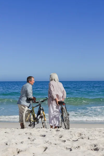 Starszy para z ich rowery na plaży — Zdjęcie stockowe