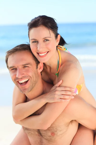 Człowiek mając żonę piggyback na plaży — Zdjęcie stockowe