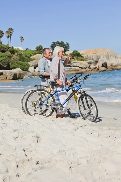 Seniorenpaar mit Fahrrädern am Strand — Stockfoto