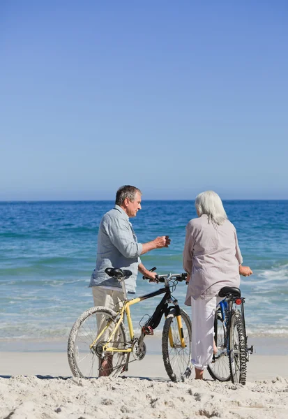 Couple aîné avec leurs vélos sur la plage — Photo