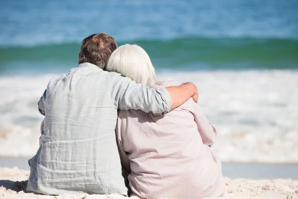 Старша пара сидить на пляжі — стокове фото