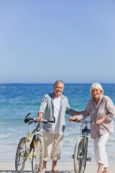 Літня пара з велосипедами на пляжі — стокове фото