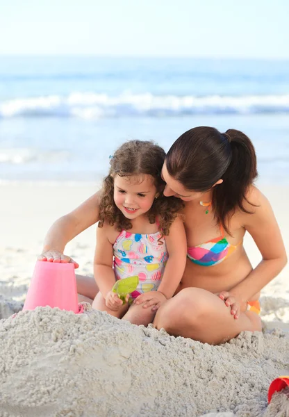 Dochter met haar moeder een zandkasteel maken — Stockfoto