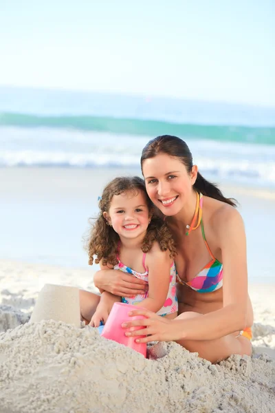 Hija con su madre haciendo un castillo de arena — Foto de Stock