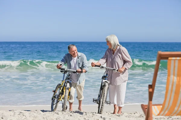 Coppia anziana con le bici in spiaggia — Foto Stock
