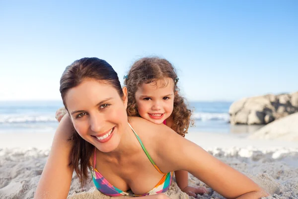 Mother and daughter lying down on the beach — Stock Photo, Image