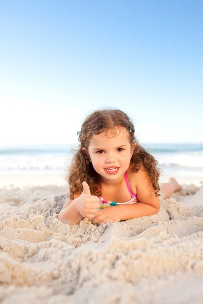 Holčička na pláži vleže — Stock fotografie