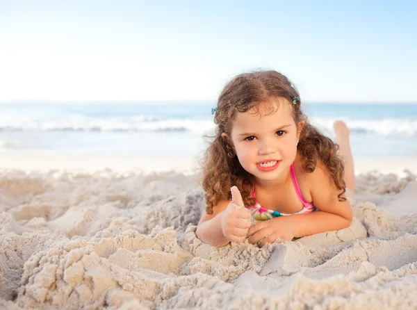 Lilla flickan liggande på stranden — Stockfoto